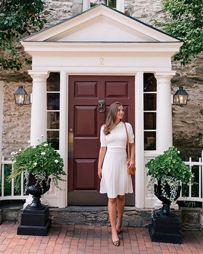 Elegant woman standing in front of historic inn entrance.