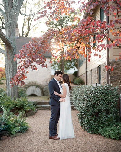 Romantic couple in wedding attire at The Red Fox Inn & Tavern, surrounded by autumn foliage, perfect.