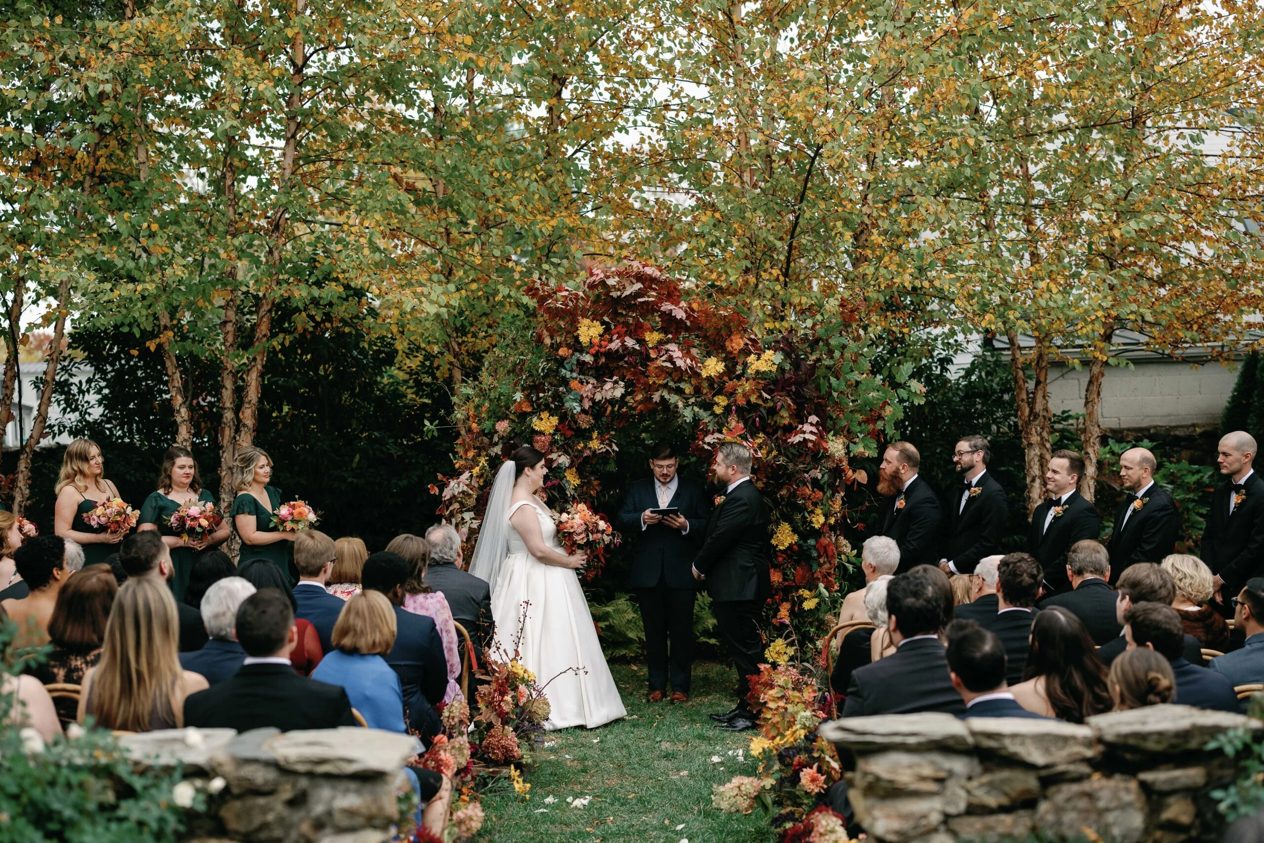 Outdoor wedding ceremony at The Red Fox Inn & Tavern with fall leaves and floral arch.