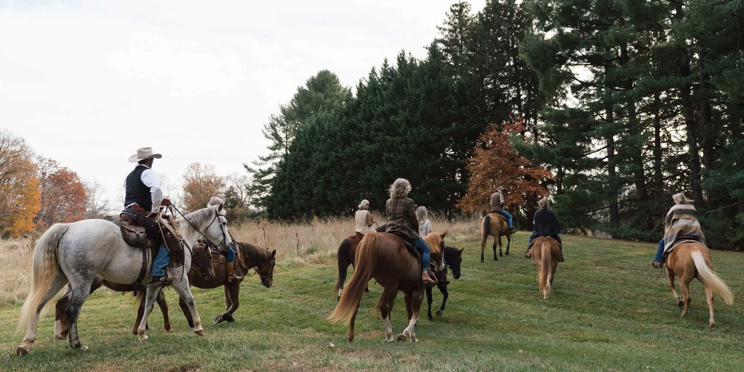 Horseback riding group at Red Fox Inn & Tavern, surrounded by autumn trees and lush greenery.
