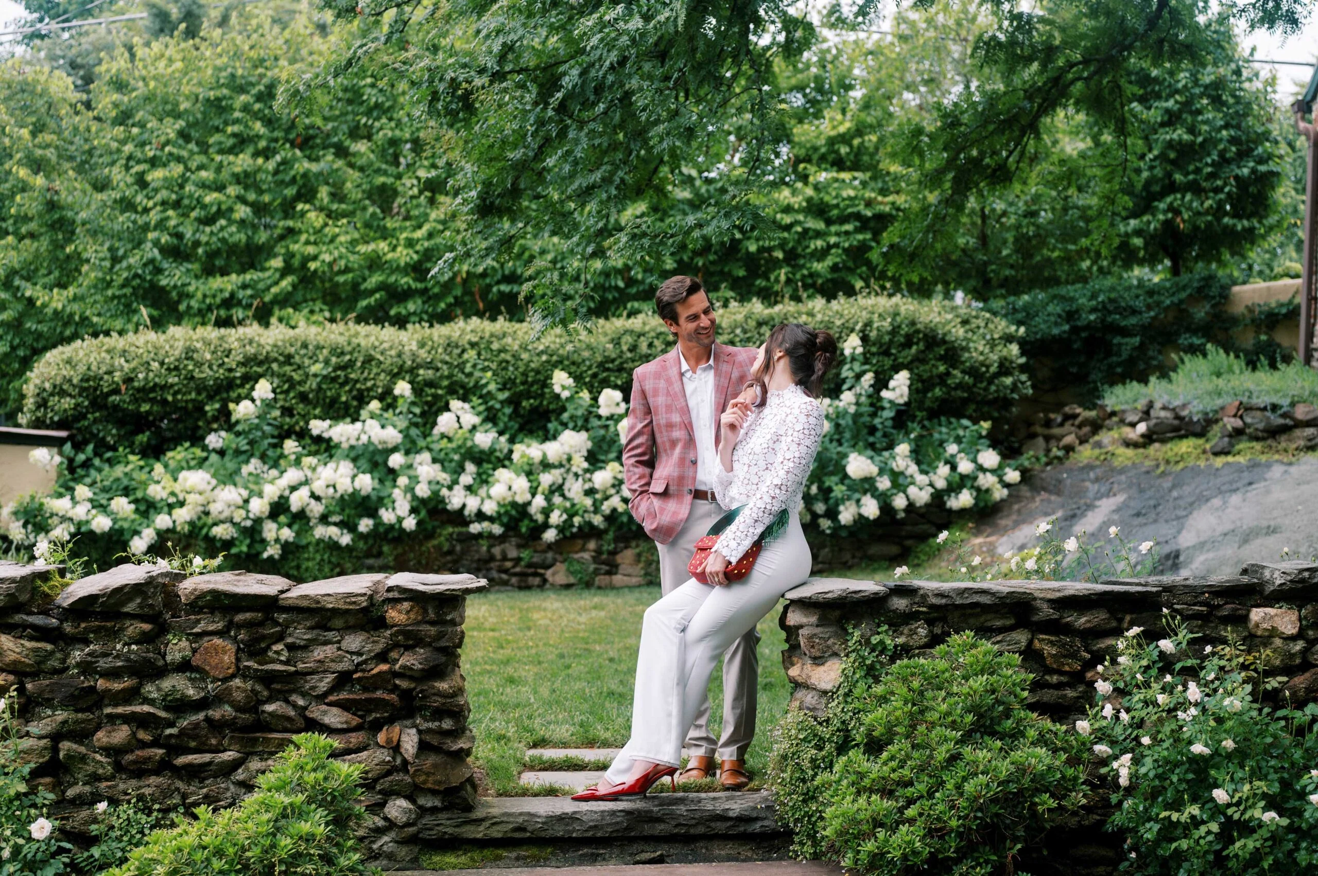 Romantic couple in garden, wedding venue, outdoor setting, lush greenery, wedding contact.
