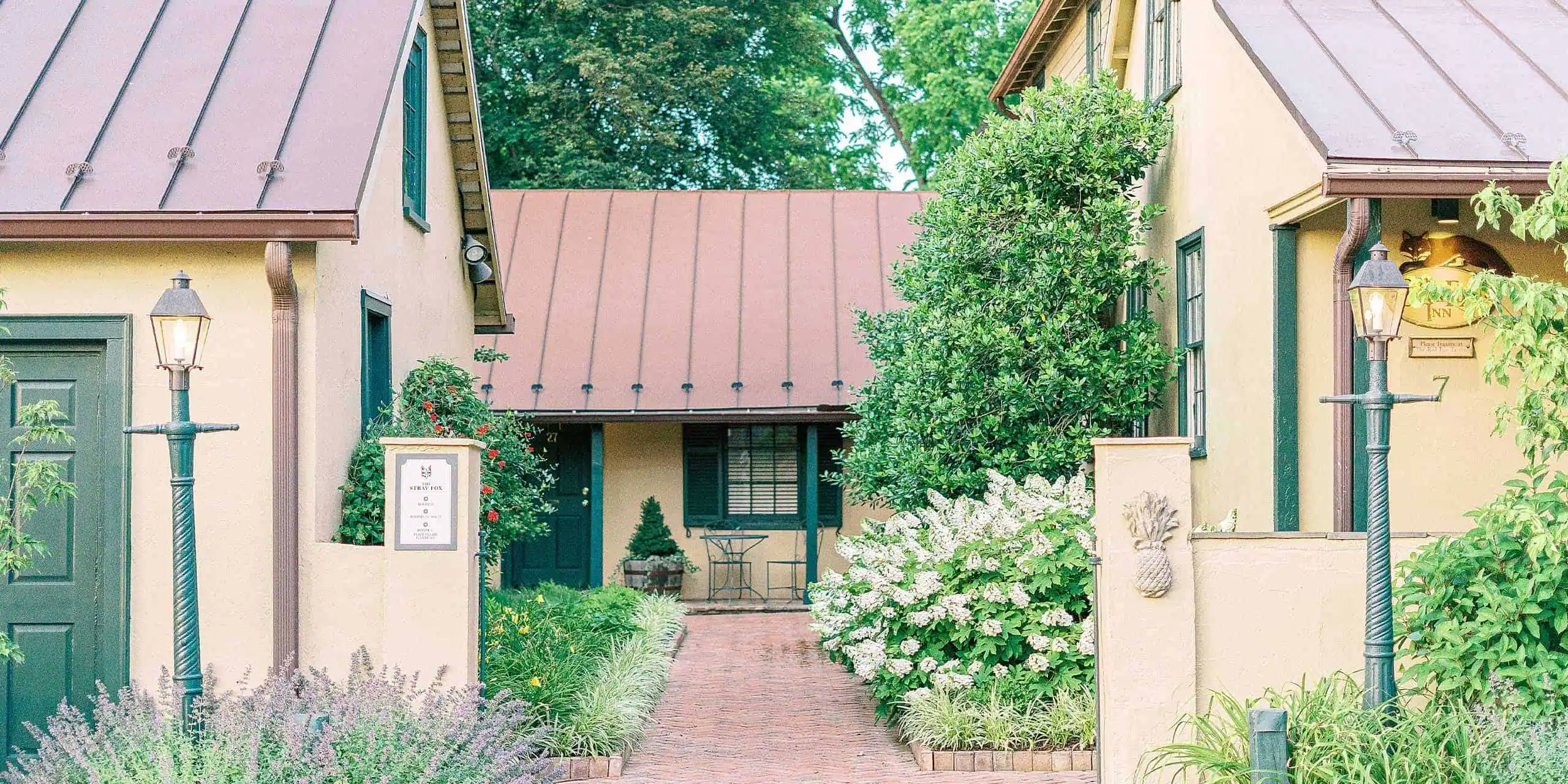 Elegant inn entrance with lush landscaping and vintage street lamps in Middleburg, VA.