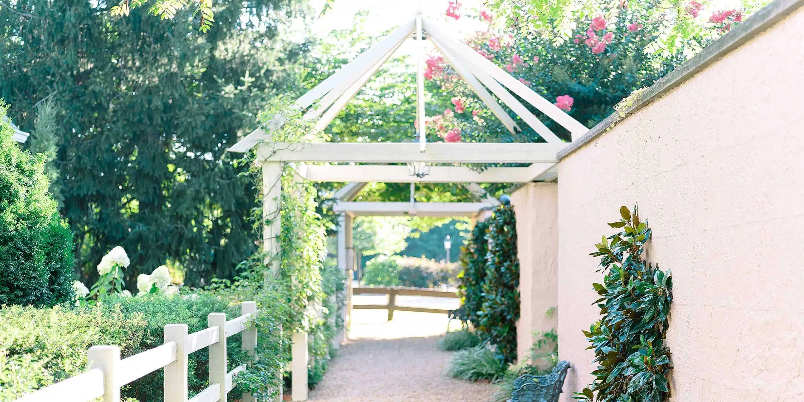 Beautiful outdoor scene with lush greenery, flowering plants, and a white pergola.