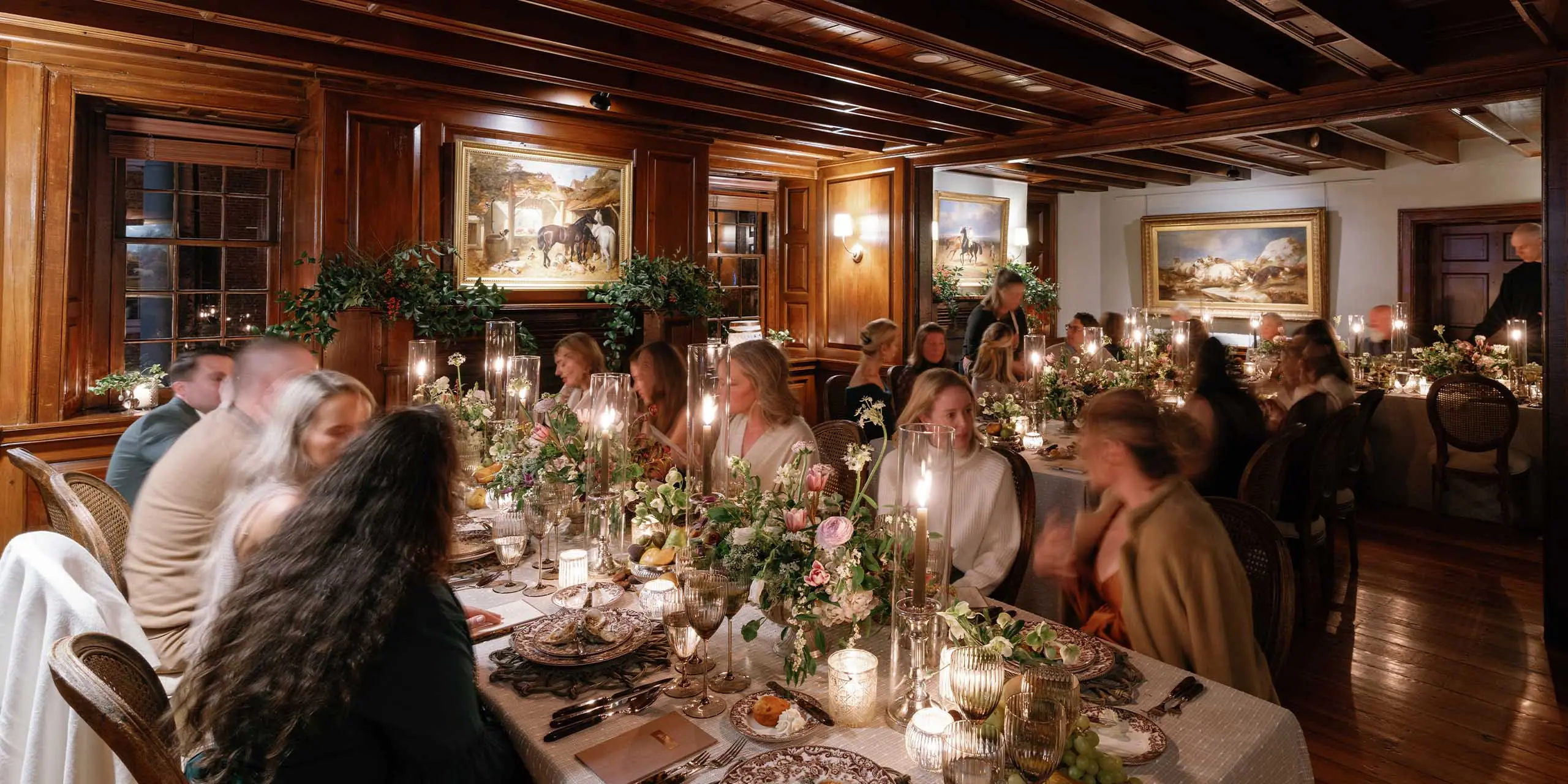 Historic inn and tavern interior with warm wood paneling, classic artwork, and candlelit tables in M.