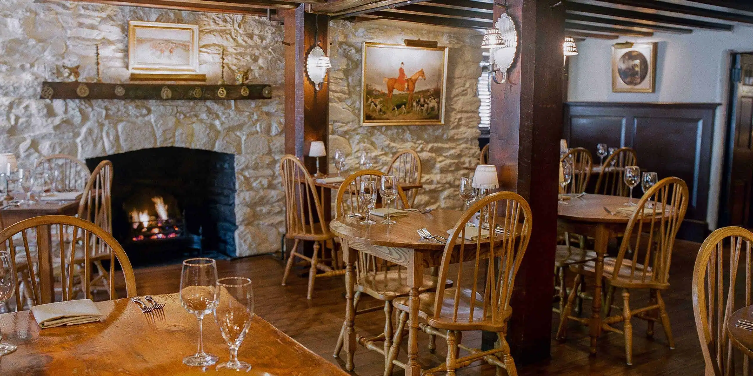 Charming interior with stone walls, wooden furniture, and elegant table settings.