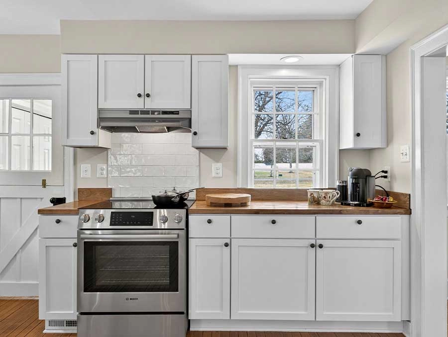 Modern kitchen at The Red Fox Inn & Tavern with white cabinets and stainless steel appliances.