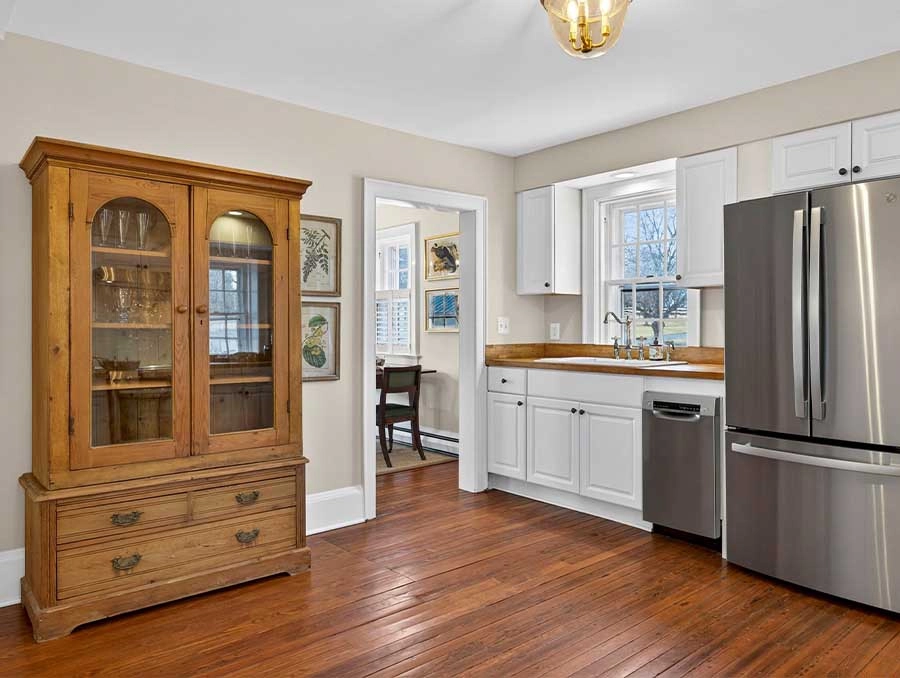 Bright kitchen featuring white cabinets, stainless steel refrigerator, and hardwood floors.