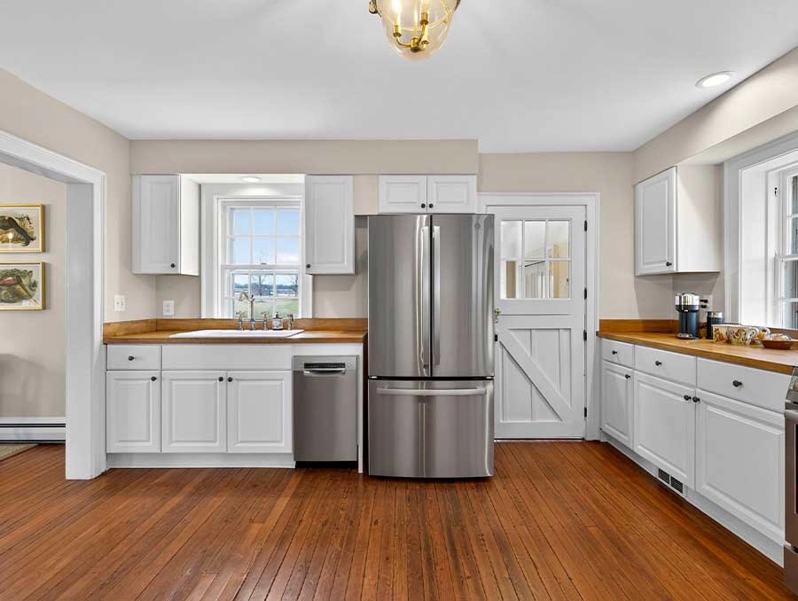 Bright Cedar Cottage kitchen with white cabinets and stainless steel appliances.