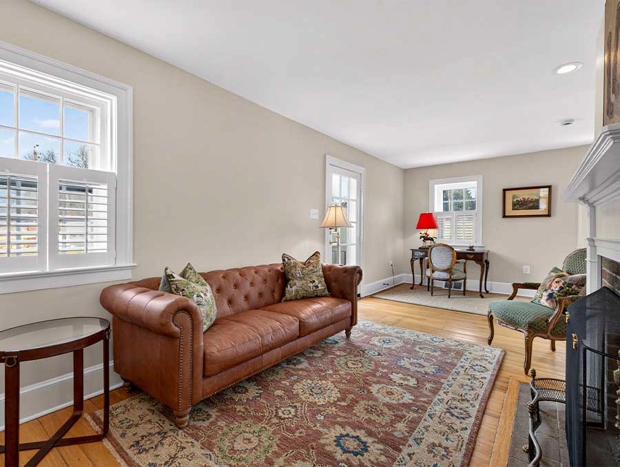 Charming living room with a leather sofa, vintage armchairs, and natural light from multiple windows.