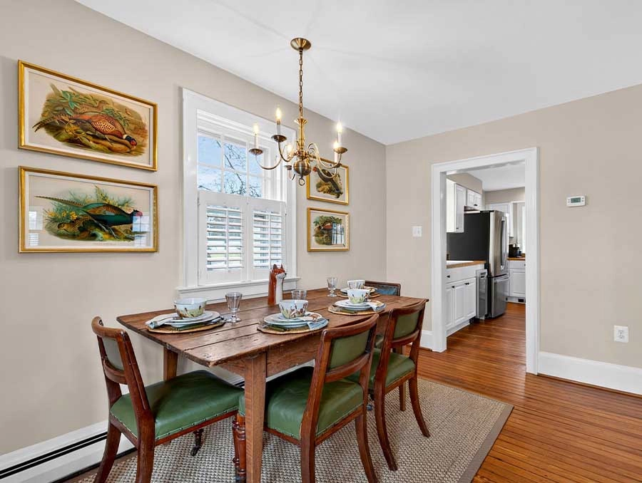 Charming dining area with a wooden table, green upholstered chairs, and wall art, perfect for family.