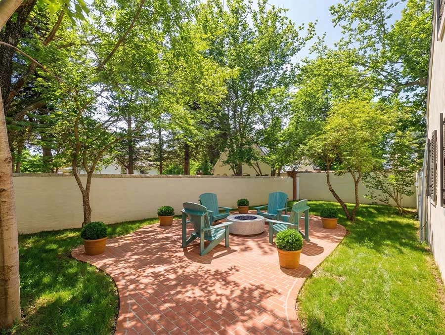 Outdoor seating area with Adirondack chairs and a fire pit, surrounded by lush greenery at Azalea Co.