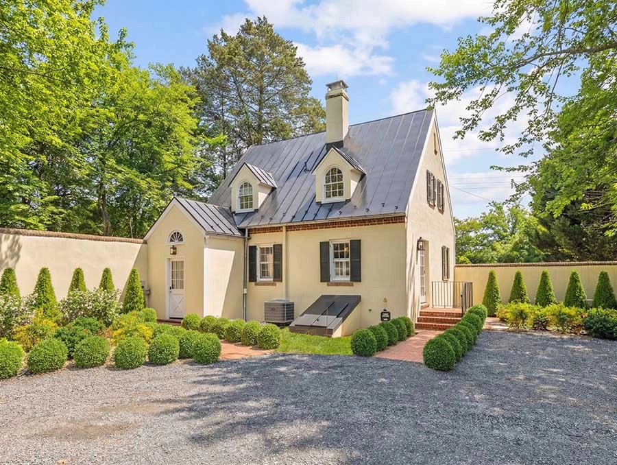 Charming Cedar Cottage with white exterior, black shutters, and lush greenery at The Red Fox Inn & T.
