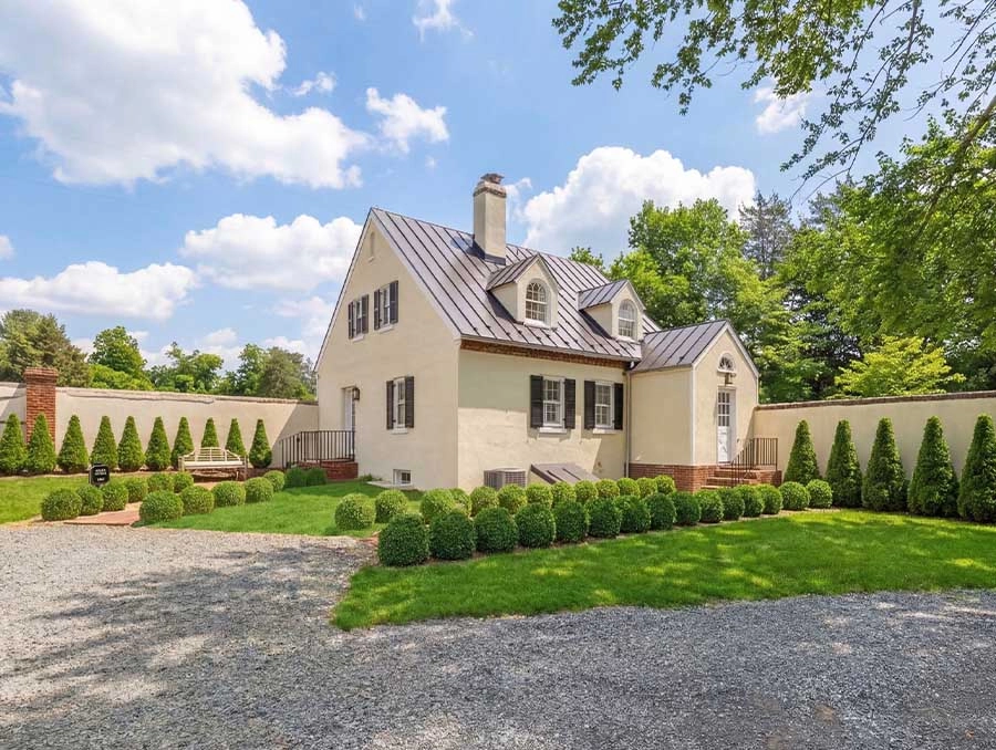 Charming white cottage with manicured lawn and lush greenery at The Red Fox Inn & Tavern.