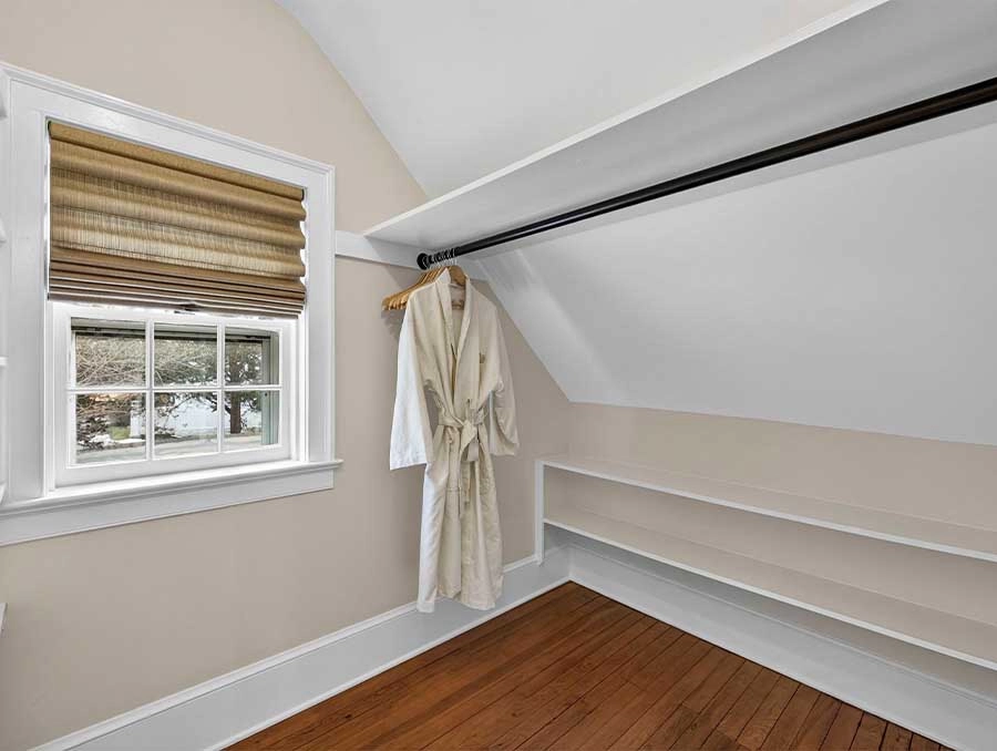 Bright attic space with window and hanging robe, perfect for relaxing or storage.