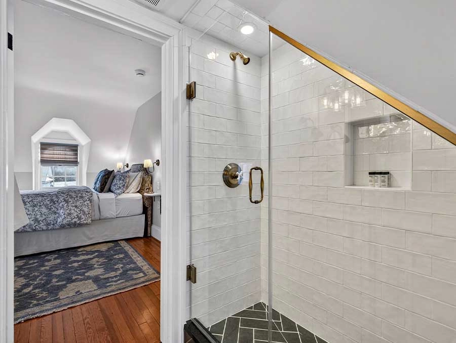 Interior view of a bedroom and adjacent modern shower at The Red Fox Inn & Tavern.