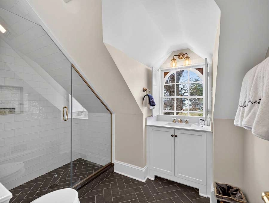 Bright bathroom with a white vanity and large window overlooking nature.